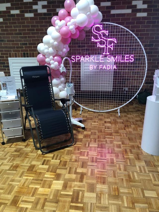 Vendor booth with neon sign and balloon arch at an Urban Pop Ups community market